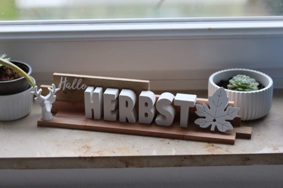 Herbst-Schriftzug Textdeko aus Buchstaben die HERBST ergeben, mit Hirschkopf und Blatt